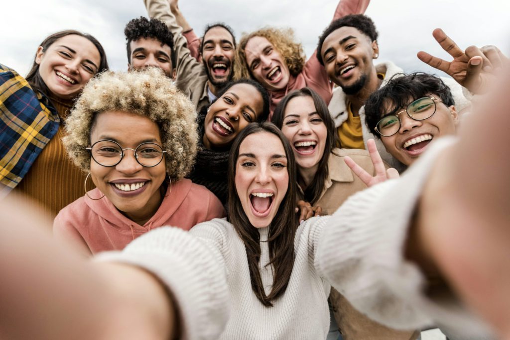 Multiracial friends taking big group selfie shot smiling at camera